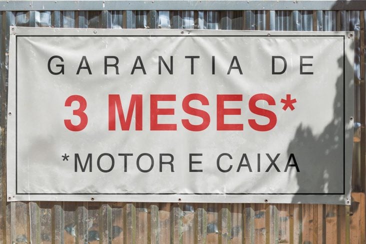 Placa branca com os escritos " Garantia de 3 meses motor e caixa"