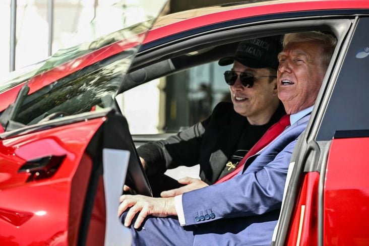 Donald Trump e Elon Musk sentados em um Tesla Model S vermelho com as portas abertas