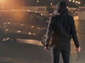 Homem com roupas pretas e uma chave de fenda na mão olha para o carro. carro roubado