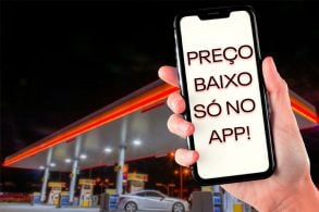 Imagem de um posto de gasolina ao fundo desfocado, em primeiro plano uma mao segurando um celular, na tela escrito: Preço baixo só no app. Postos de combustível