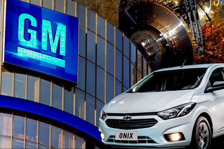 Montagem foto do prédio da GM ao fundo correia dentada banhada a óleo, na frente dos elementos carro Onix 2020 branco em destaque.