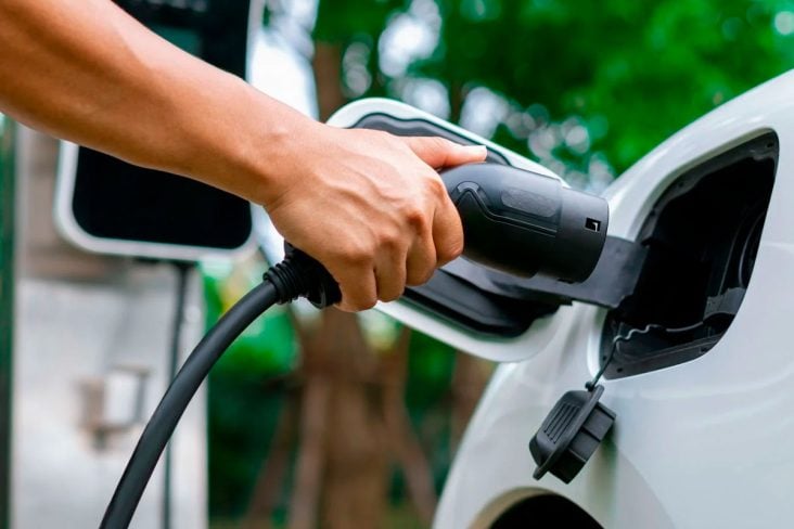 carregadores de carros elétricos mão de pessoa plugando um carregador em carro elétrico ou híbrido plug in branco. autonomia carro elétrico