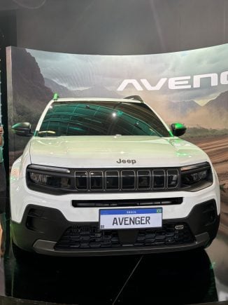 Jeep Avenger branco frente com banner atrás escrito o nome do veículo
