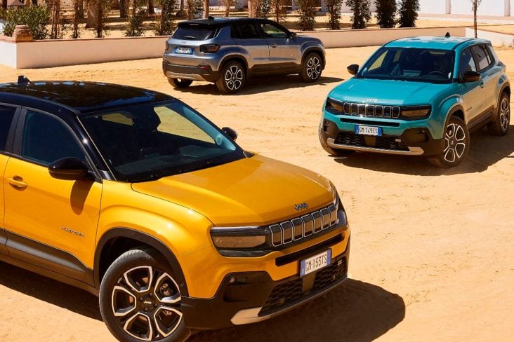 Três Jeeps Avenger das cores amarelo, azul e prata estacionados a frente de uma casa no estilo Espanhol.