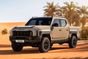 kia tasman x pro cabine dupla bege frente parada em oásis no deserto.