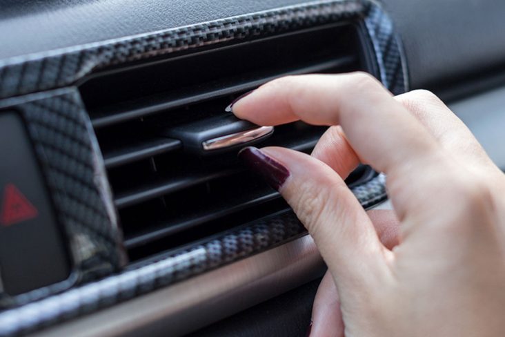 Mulher abre o ar condicionado do carro