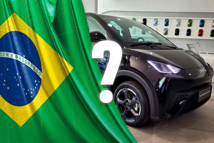 BYD Dolphin Mini 2025 preto versão de cinco lugares frente parado em concessionária,A esquerda uma bandeira do Brasil.