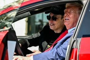 Donald Trump e Elon Musk sentados em um Tesla Model S vermelho com as portas abertas