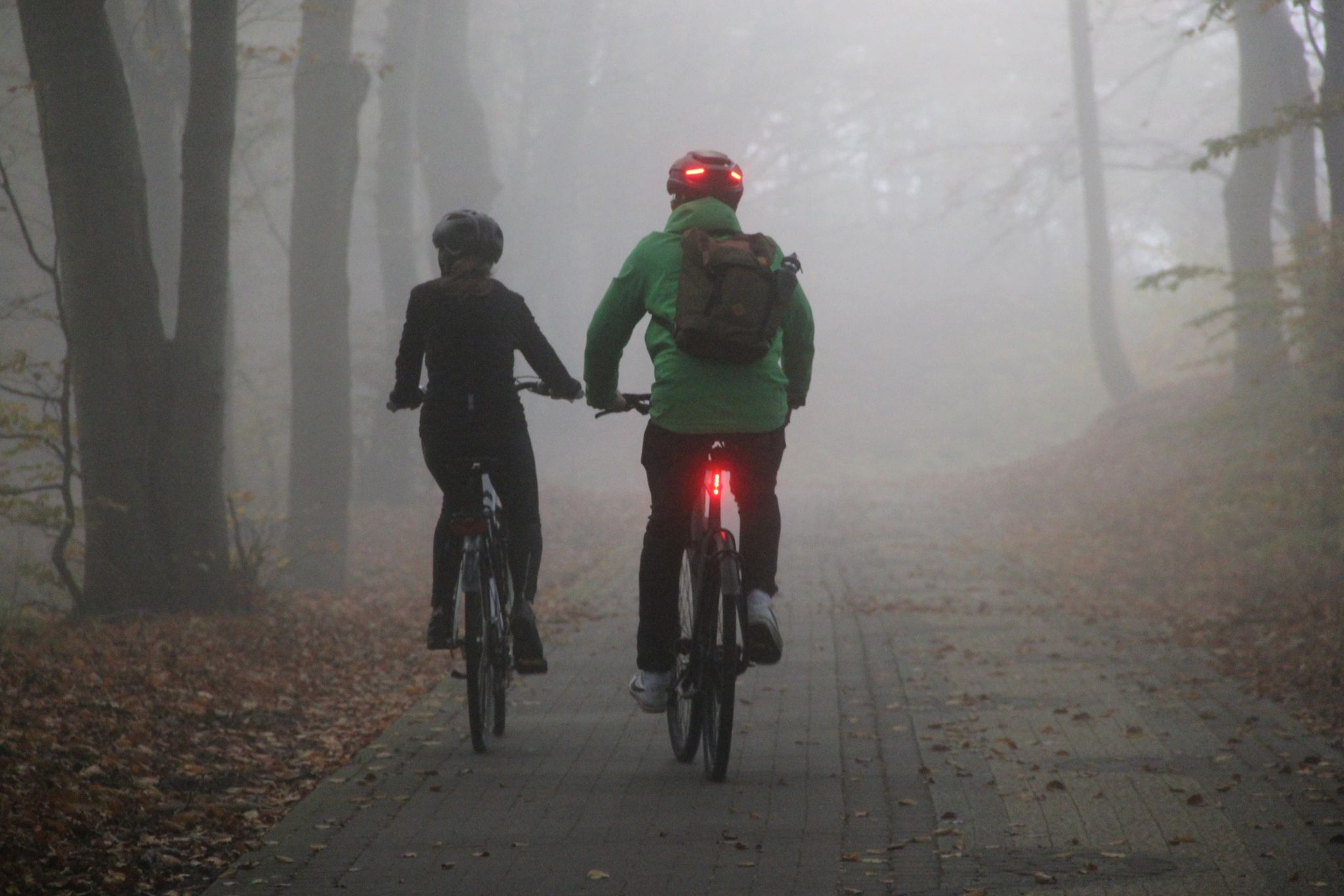 homem e mulher pedalam na neblina com luz de sinalizacao foto shutterstock