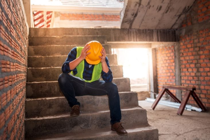 trabalhador construcao triste sentado na escada