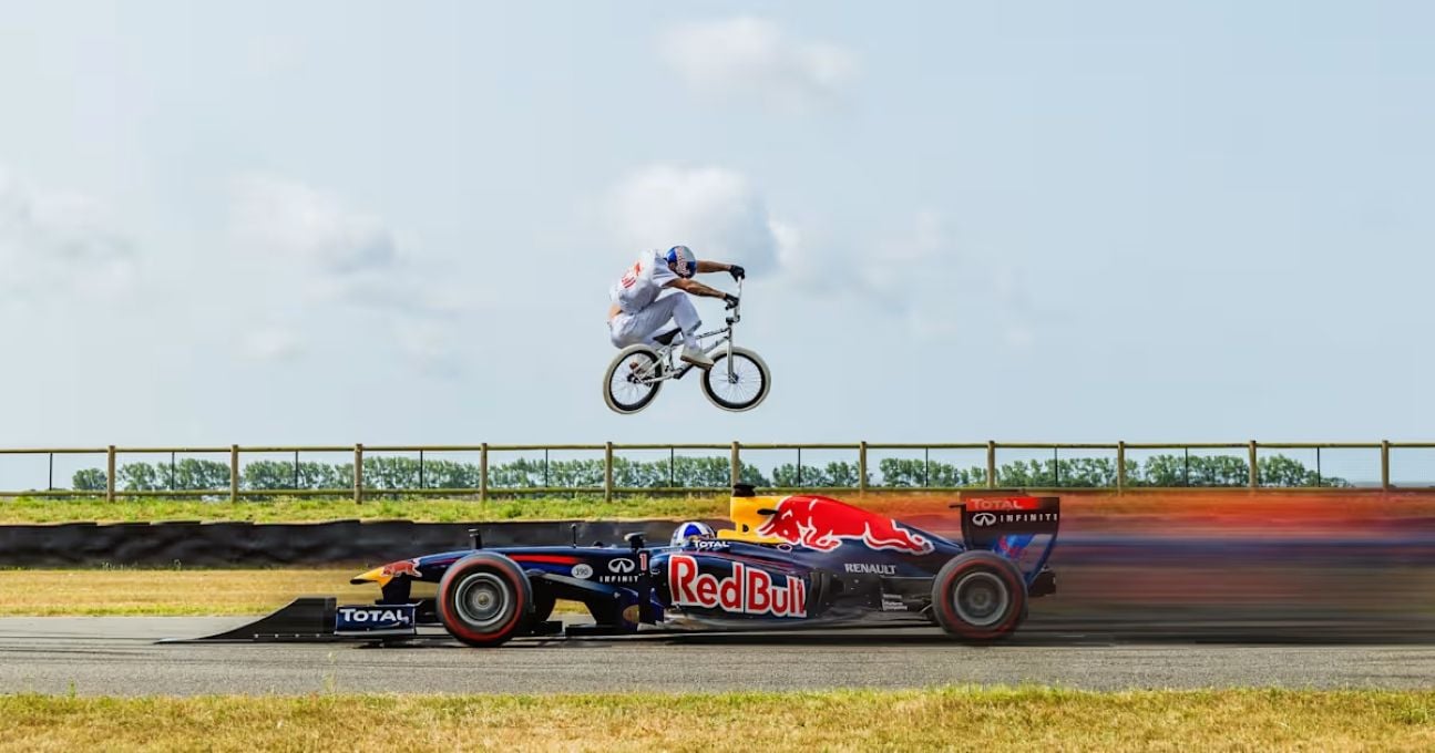 Ciclista salta sobre carro de F1 em movimento