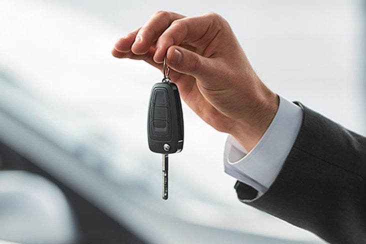 carro assinatura, homem segurando chave do carro em destaque.