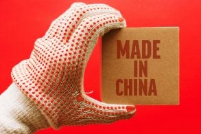 UMA MÃO COM LUVAS SEGURA UM PACOTE ESCRITO MADE IN CHINA