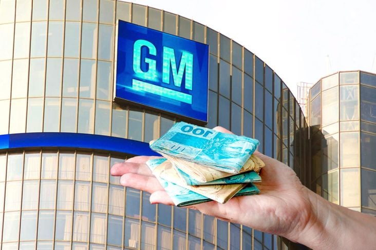 Sede da General Motors (GM), mão com notas de 100 reais bem visíveis.