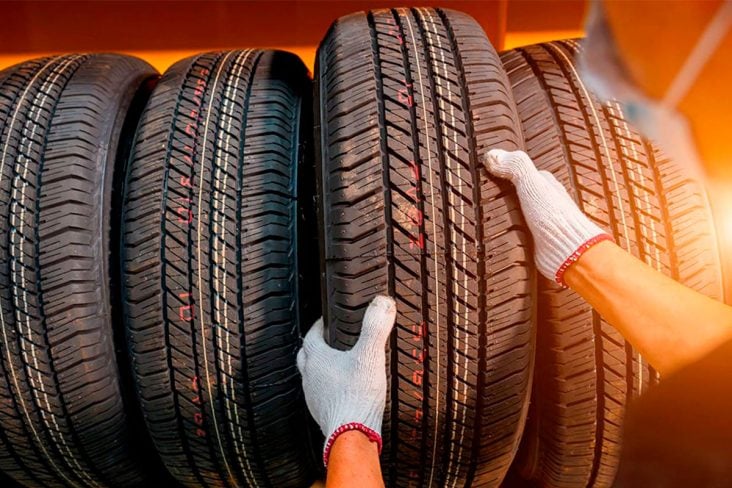 UMA PESSOA COM MÁSCARA E LUVAS PEGA UM PNEU NOVO NA PRATELEIRA DE PNEUS