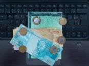 Shutterstock documento licenciamento sobre computador com notas de dinheiro e moedas