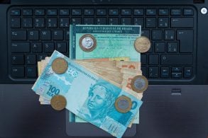 Shutterstock documento licenciamento sobre computador com notas de dinheiro e moedas