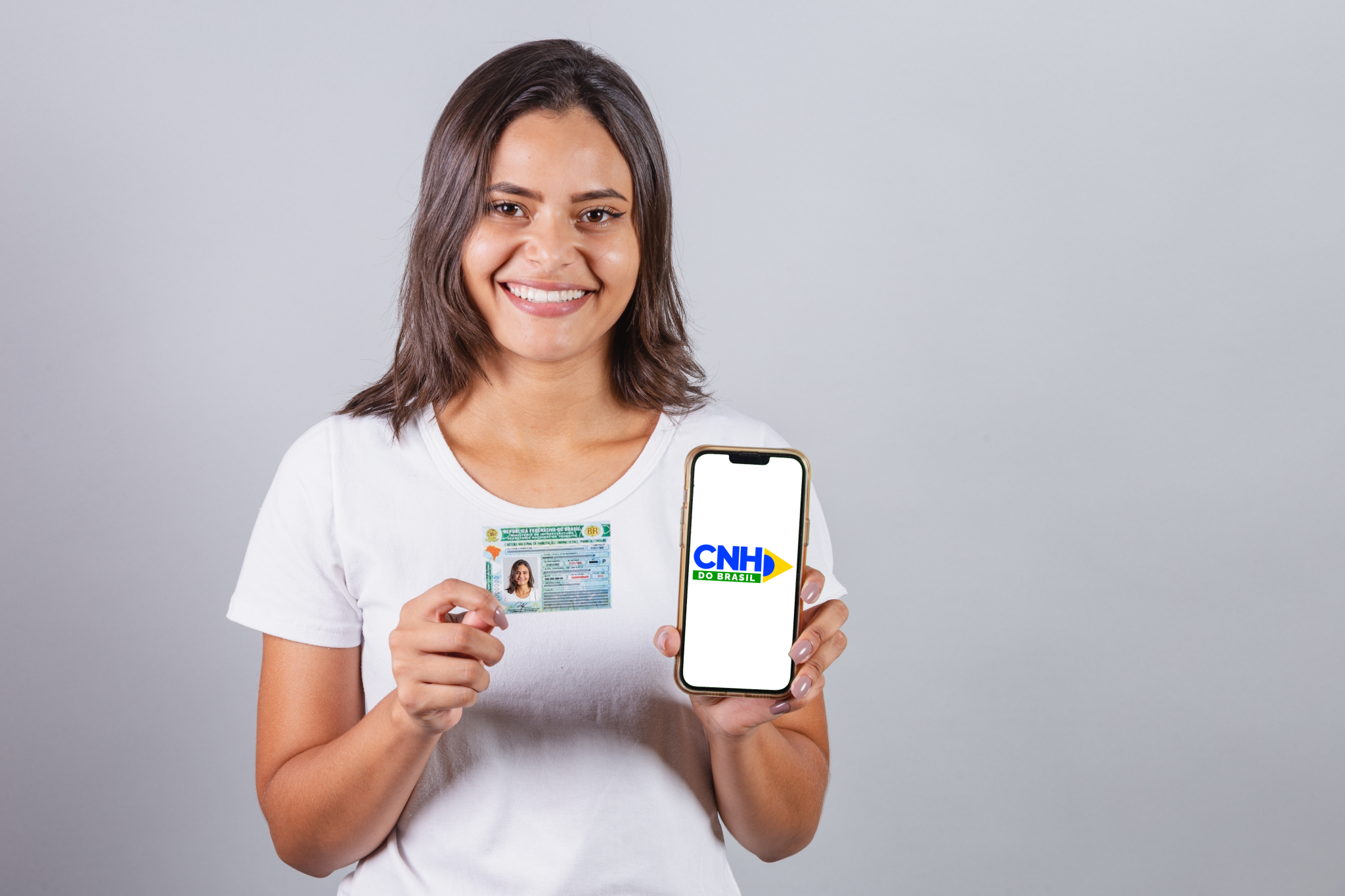 shutterstock Mulher segurando celular com app CNH do Brasil e documento impresso da habilitação