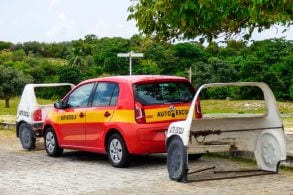 volkswagen up vermelho de autoescola estacionado entre dois carros