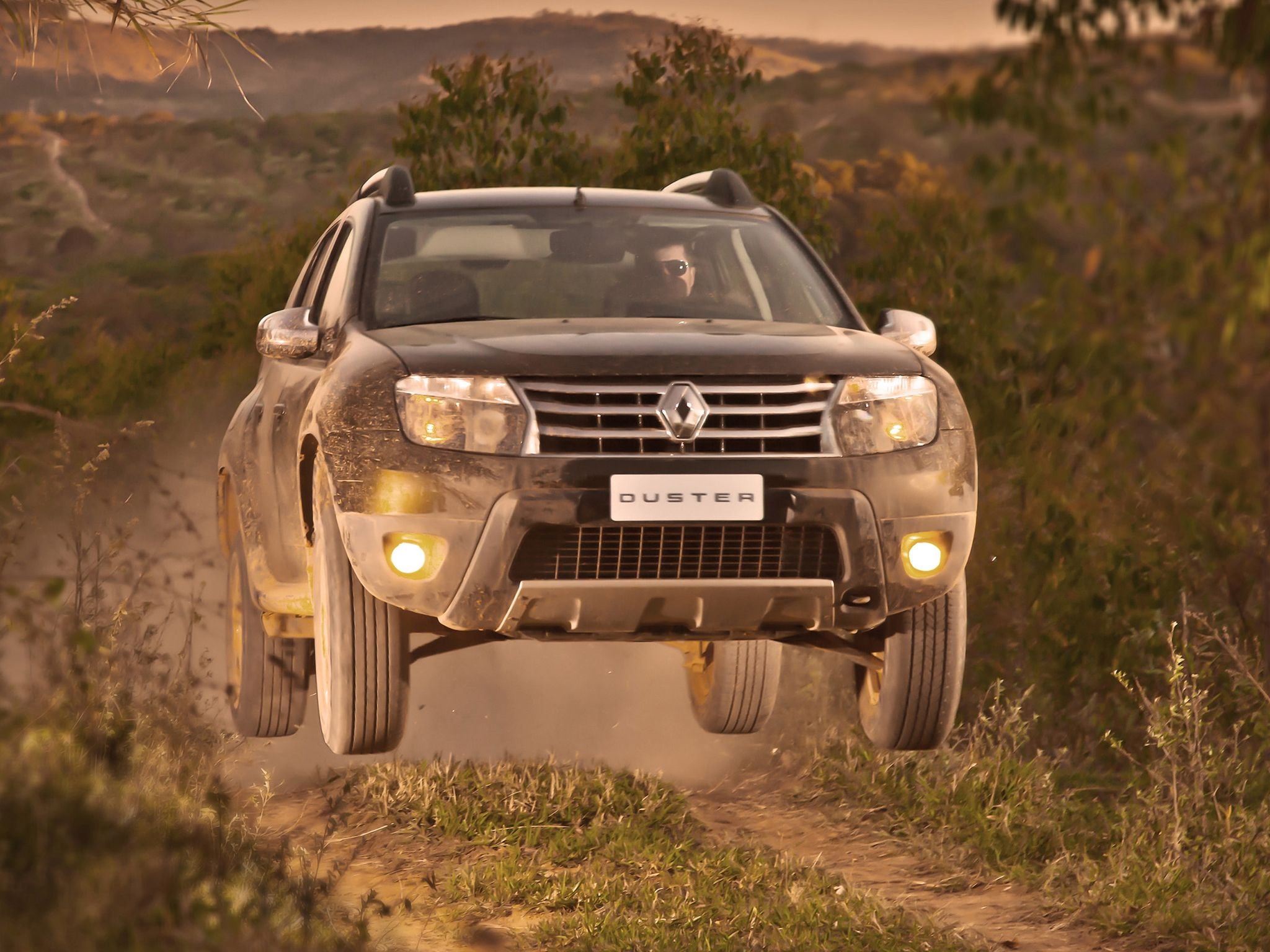 renault duster 4wd marrom frente saltando em estrada de terra