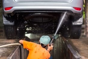 Trabalhador do lava jato pulverizando o chassi do carro