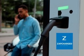 Tomada de recarga plugada no poste de abastecimento homem conversa no telefone ao fundo