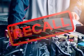 recall escrito em primeiro plano mecanico com prancheta fazendo inspeção em motor do carro em segundo plano