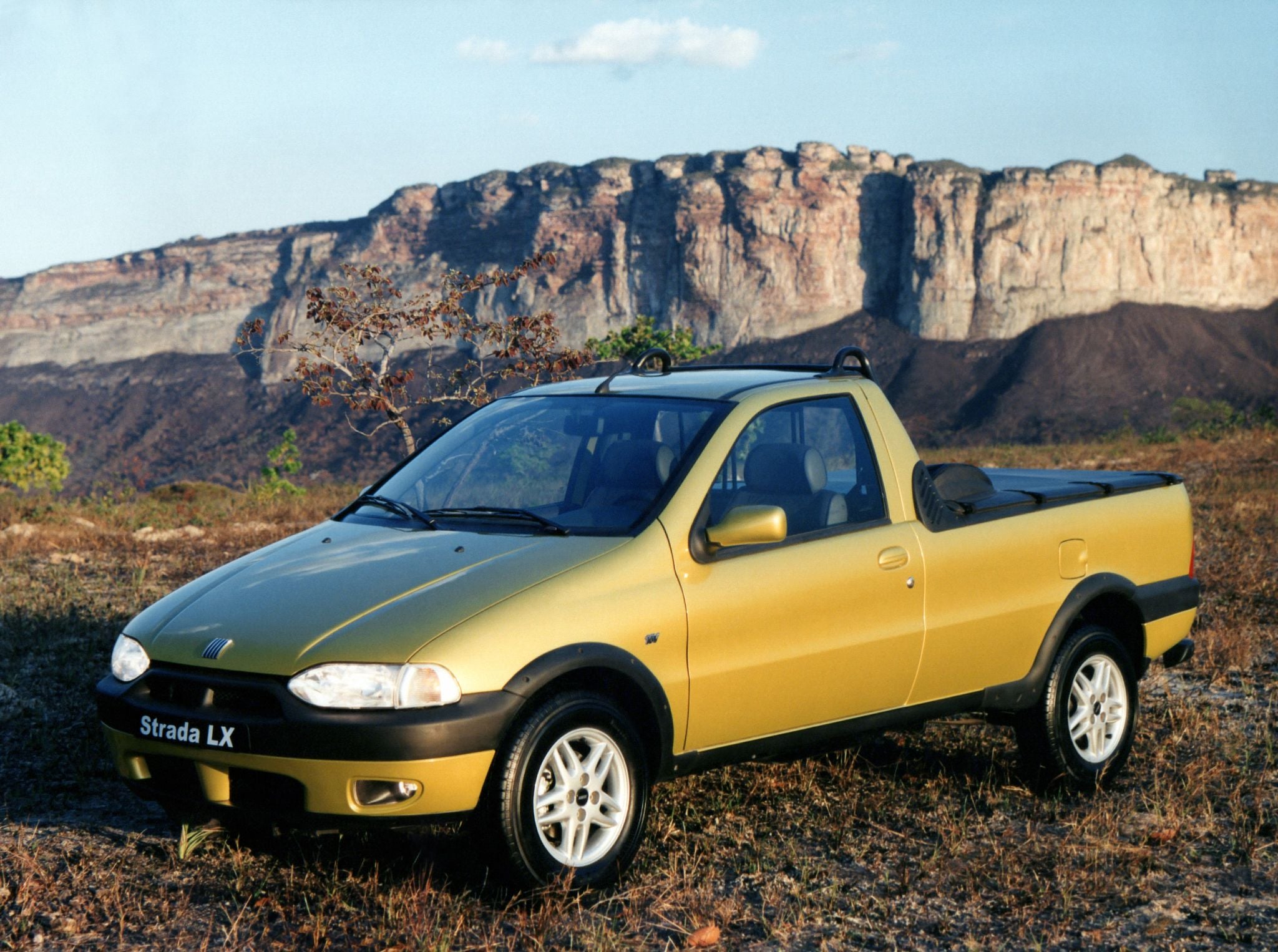 fiat strada lx 16v verde frente parada em campo
