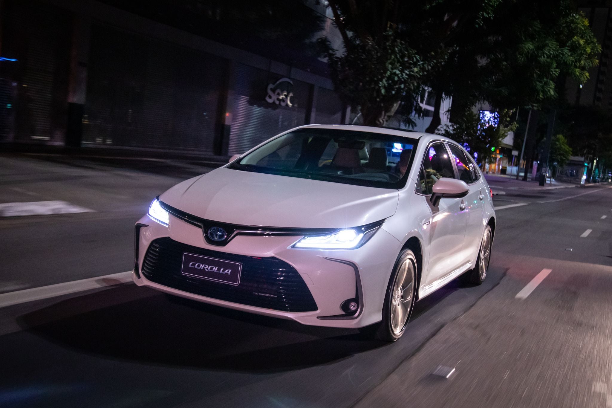 toyota corolla Altis hybrid sedan branco em movimento